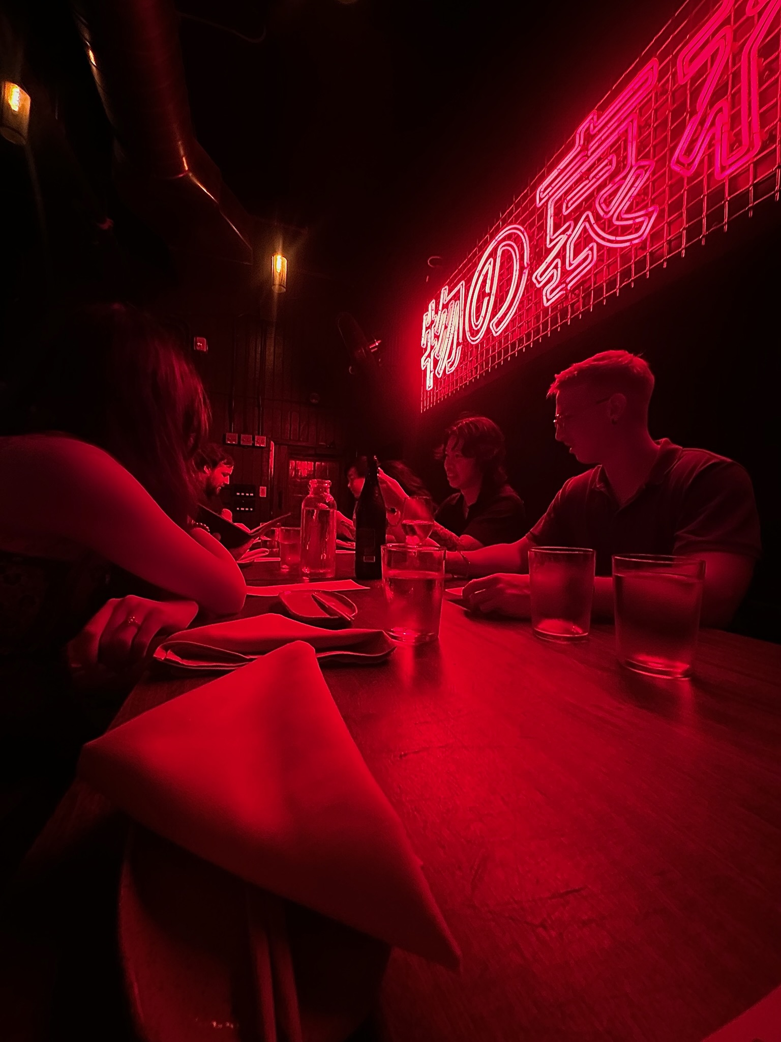 My friends sitting at a table under the red neon Japanese sign